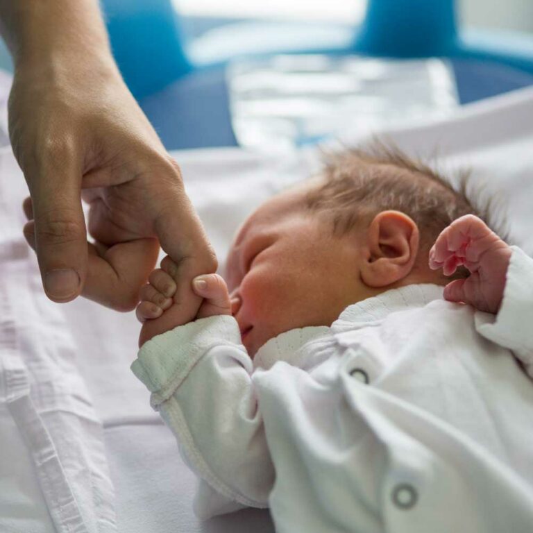 Newborn baby holding on to a grownup's finger